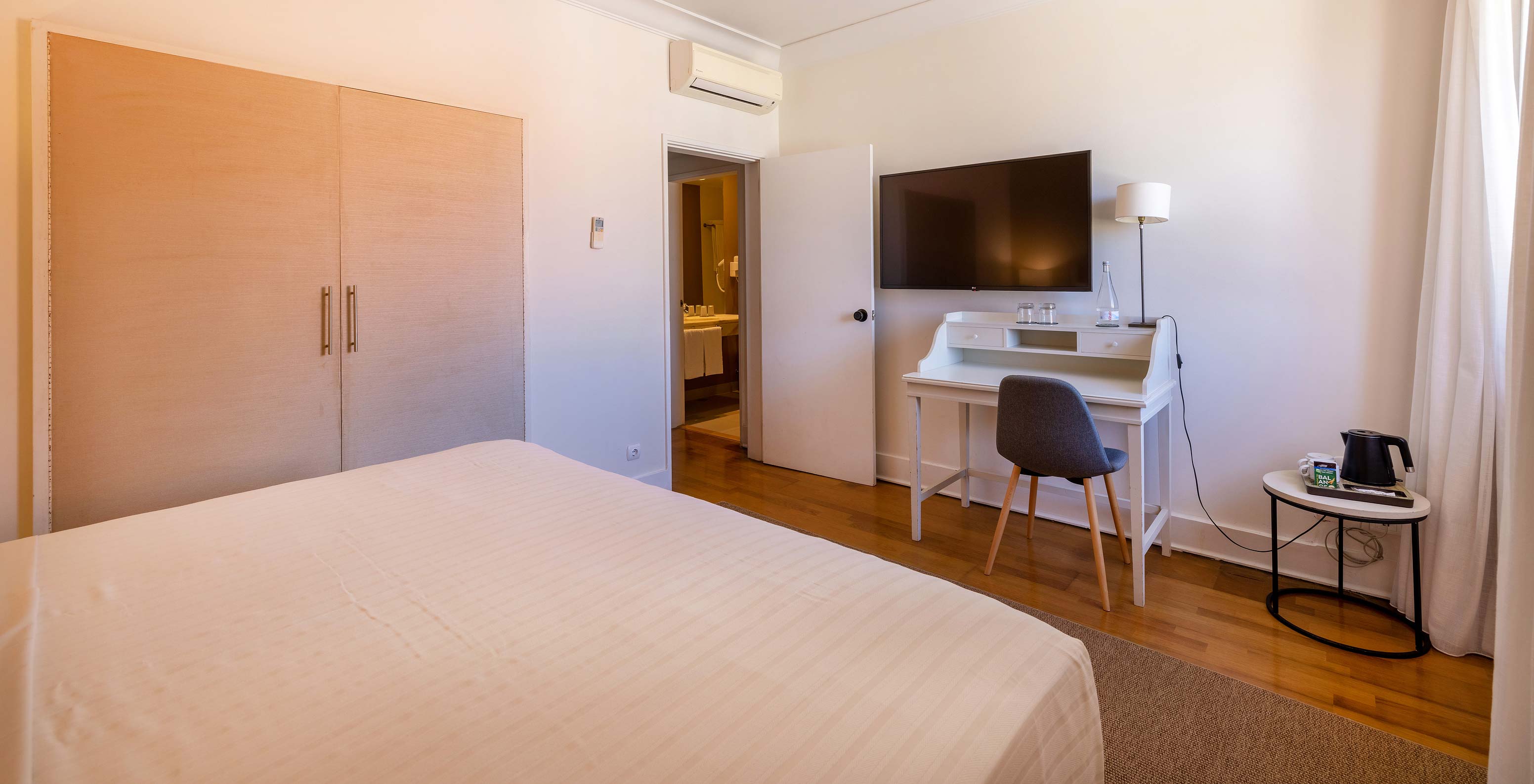 O Quarto Clássico da Pousada Sagres tem uma cama de casal, uma secretária com cadeira, televisão e ar condicionado
