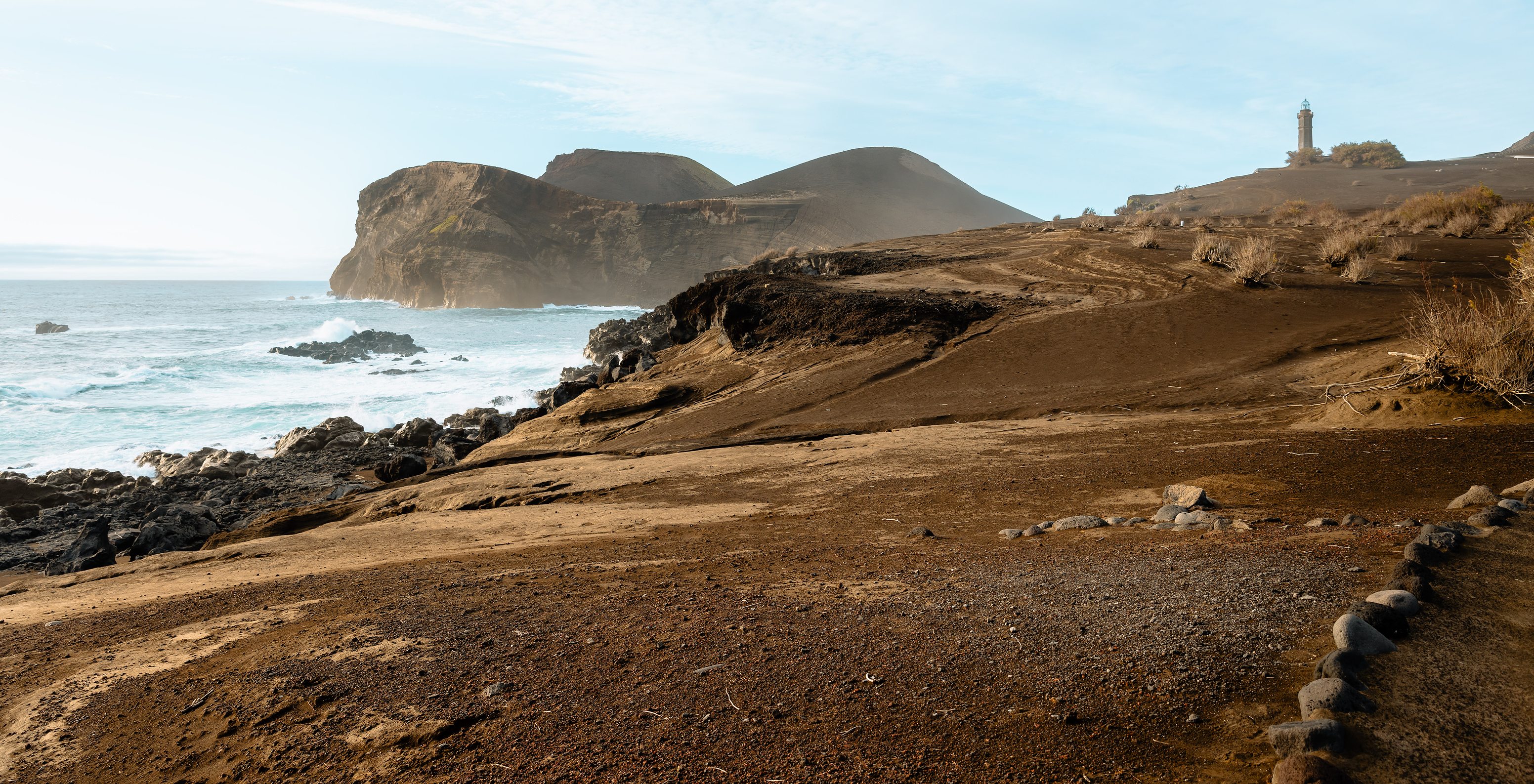 Vista panorâmica da ilha do Faial, com terra seca e castanha, e mar azul claro no horizonte