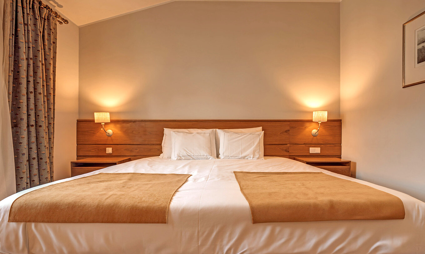 O Quarto Superior Família da Pousada Ourém tem uma cama de casal com duas mesas de cabeceira e dois candeeiros