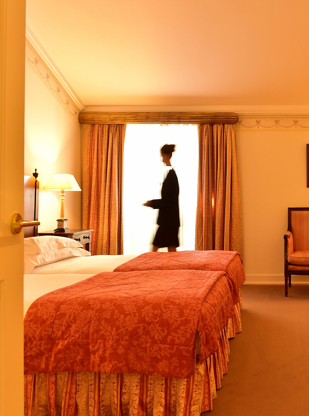 No Quarto Clássico da Pousada Palácio Queluz uma senhora prepara o quarto para receber os próximos hóspedes