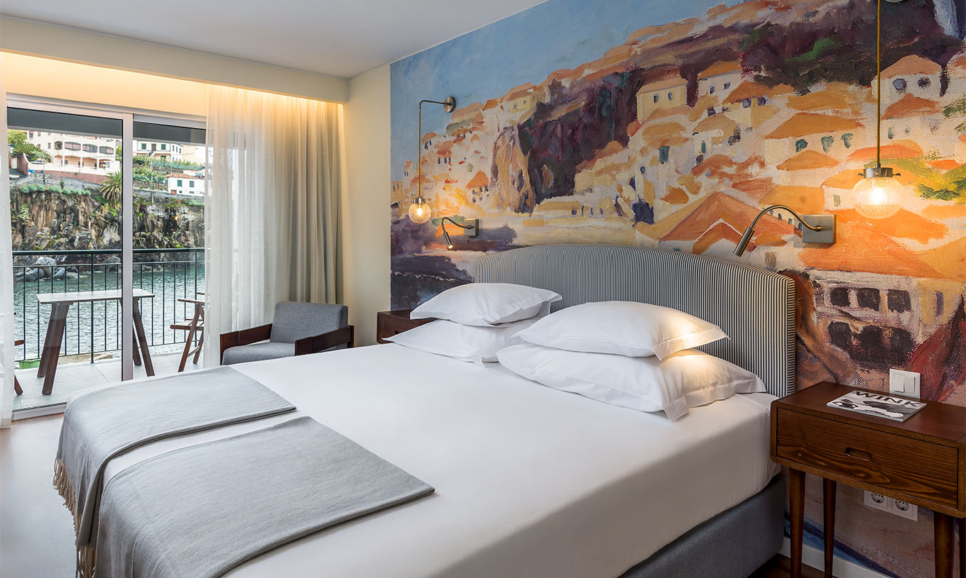 O Quarto Deluxe Superior Family Bay View do Pestana Churchill Bay tem tons cinzentos, com uma cama de casal e varanda