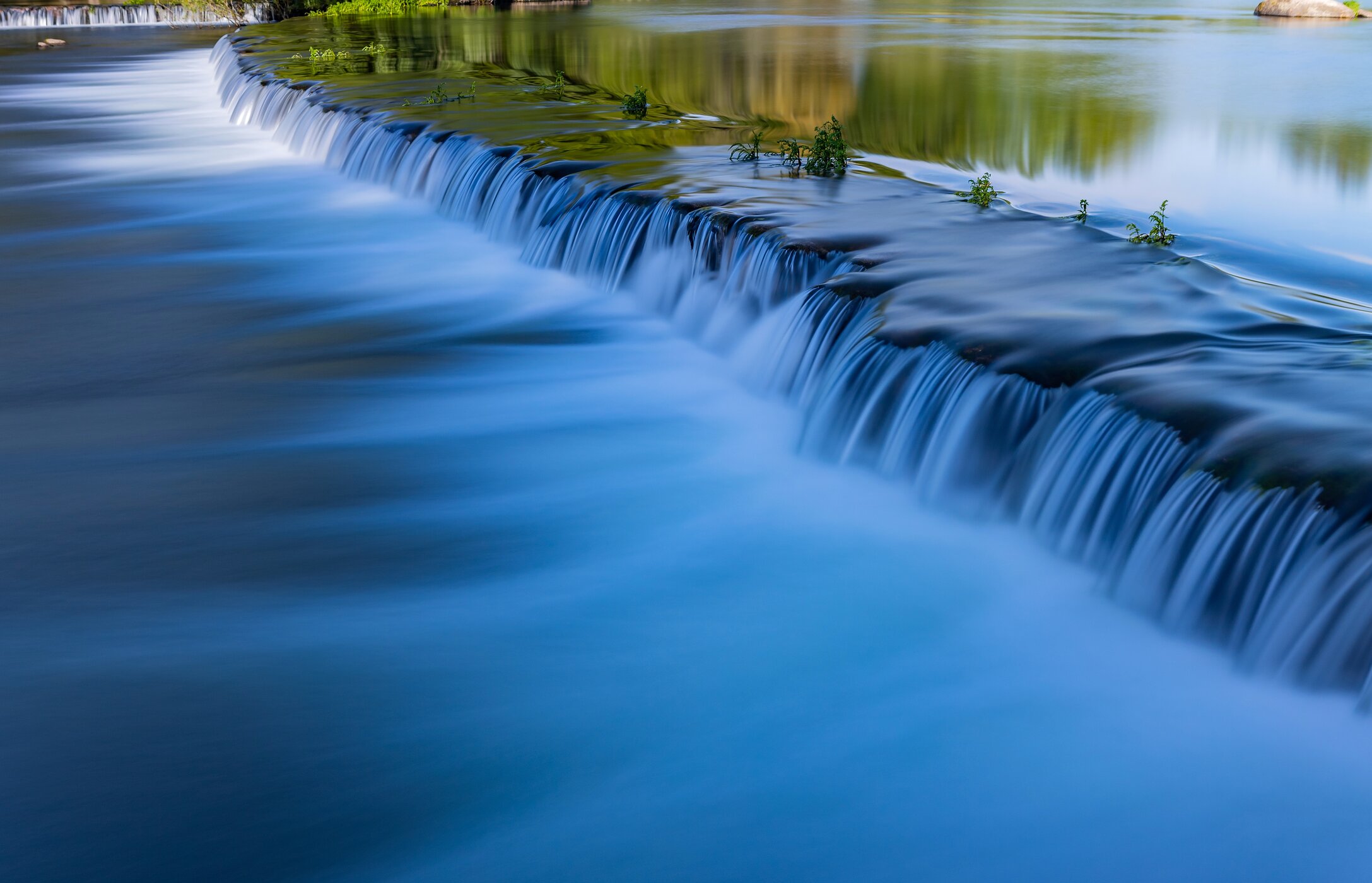 Vista panorâmica da Praia de Adaufe, com águas cristalinas, cercada por rochas e vegetação