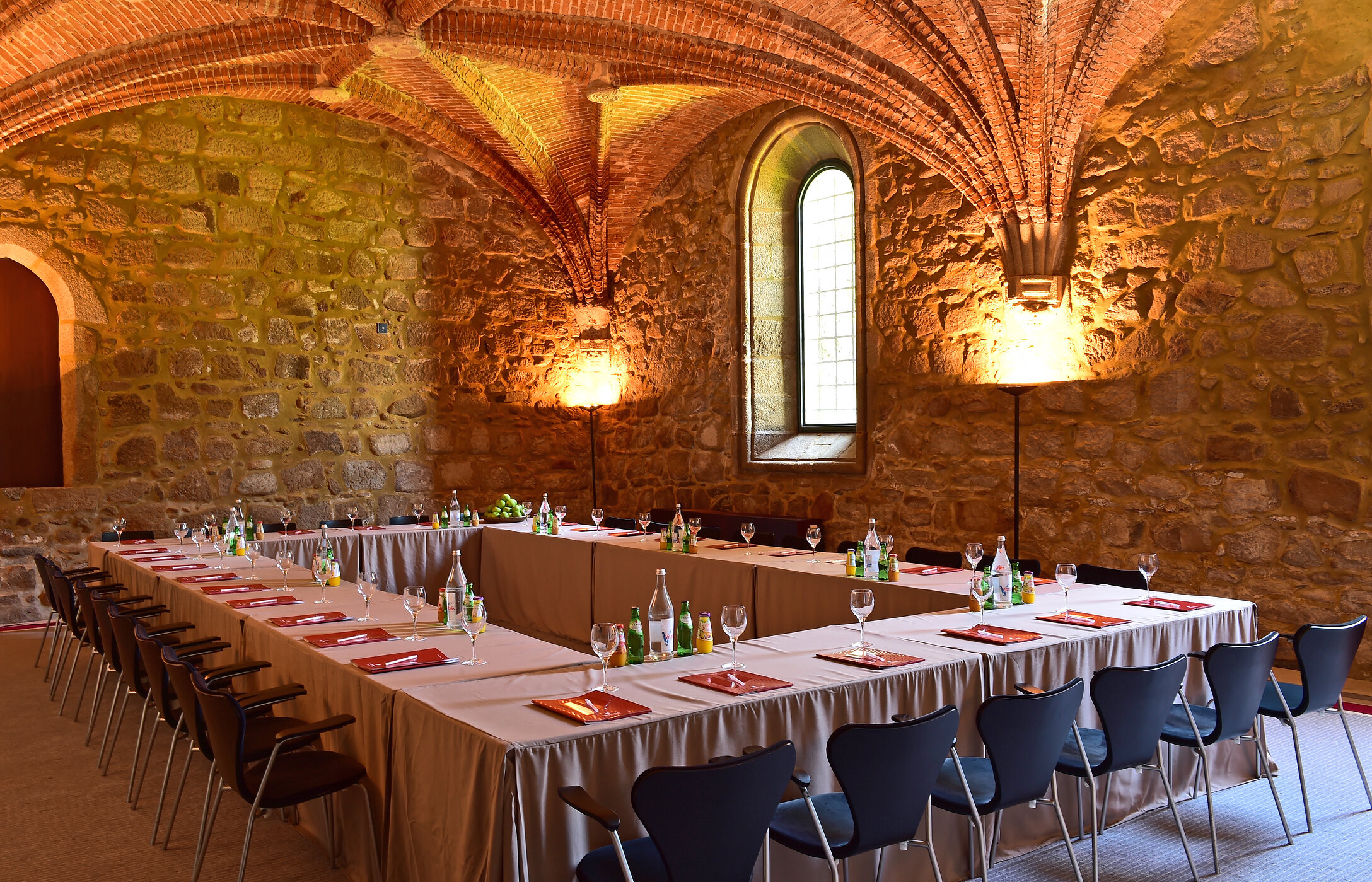 Sala para reuniões ou conferências, com design rústico e elegante, paredes de pedra, teto abobadado e mesa com bebidas