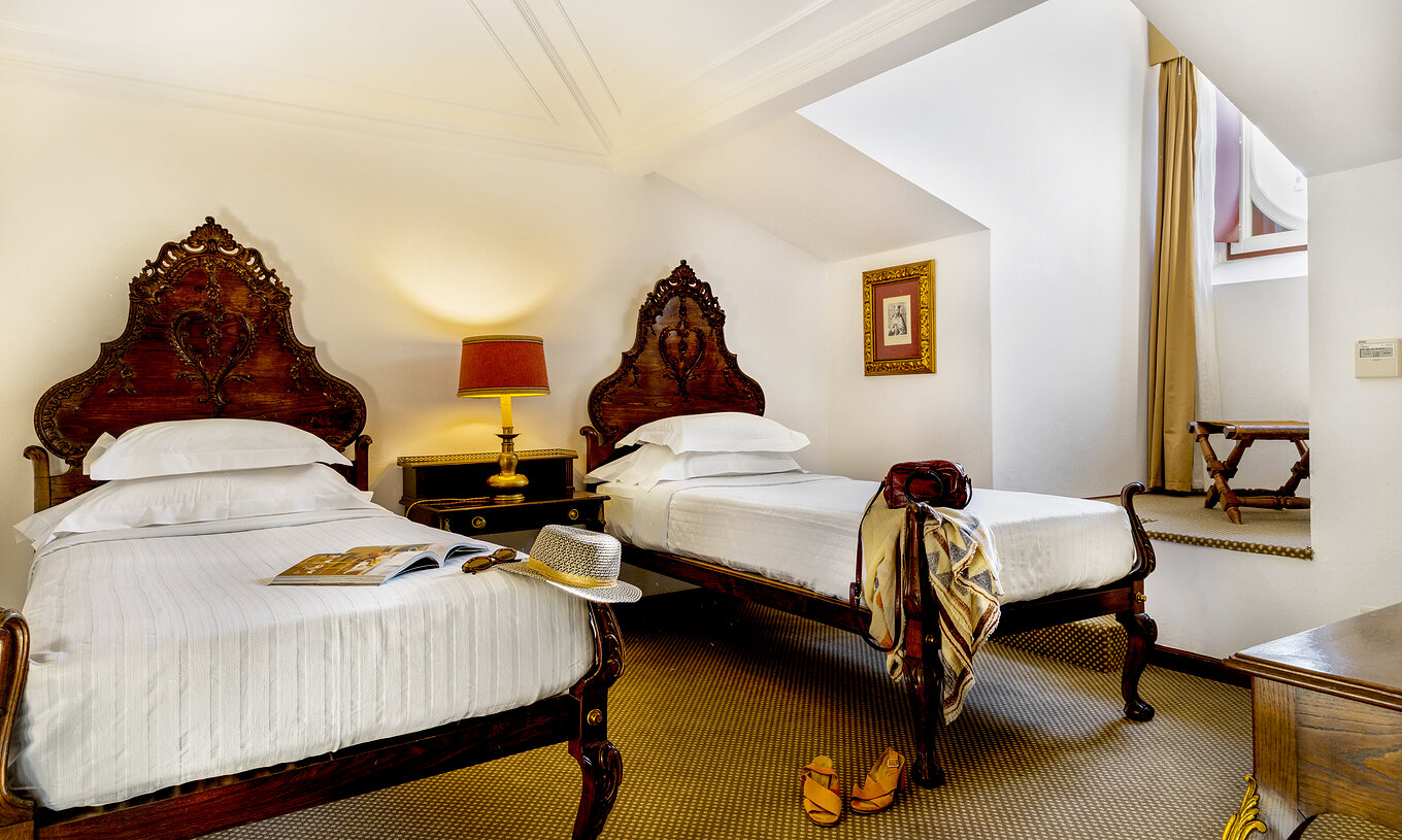 O Quarto Clássico da Pousada Castelo Estremoz tem duas camas individuais e uma mesa de cabeceira com candeeiro