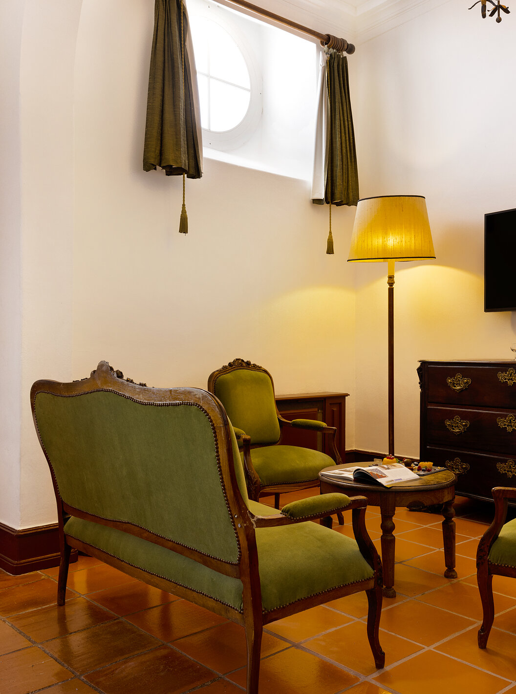 A Junior Suite da Pousada Castelo Estremoz tem uma sala com sofás, um espelho e uma televisão