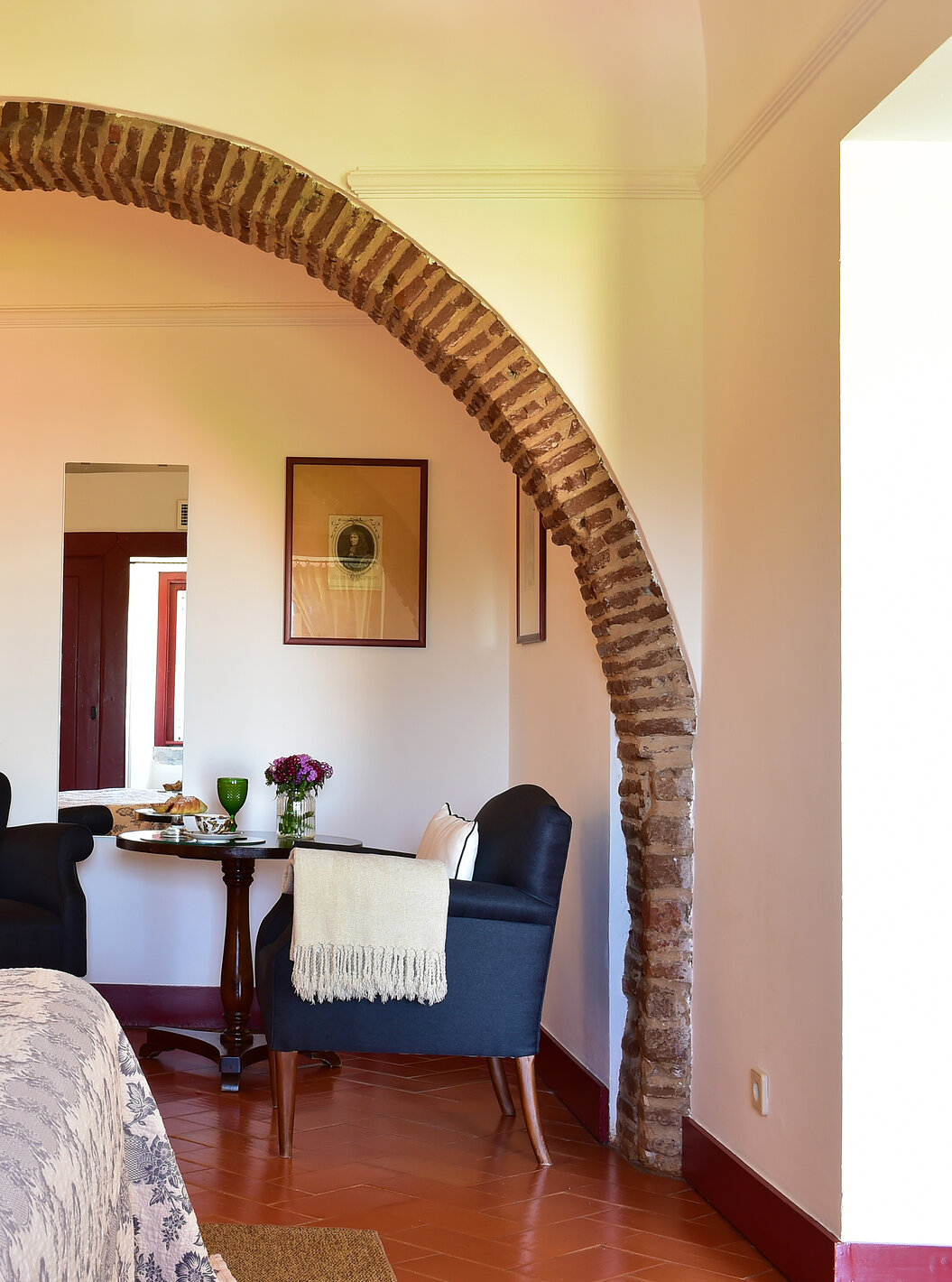 A Junior Suite da Pousada Convento Beja tem um arco dentro do quarto, por cima de dois cadeirões azuis para apoio
