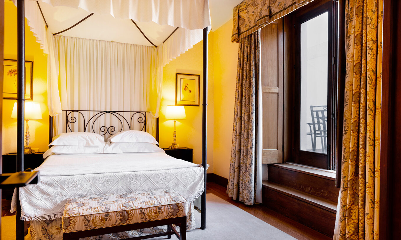 A Suite Especial da Pousada Convento Vila Viçosa tem uma cama de casal com um banco de apoio aos pés da cama