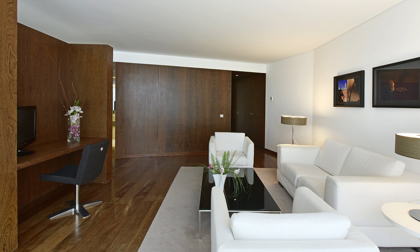 A Suite Especial da Pousada Palácio Estoi tem uma sala com sofás brancos, uma mesa de centro e televisão