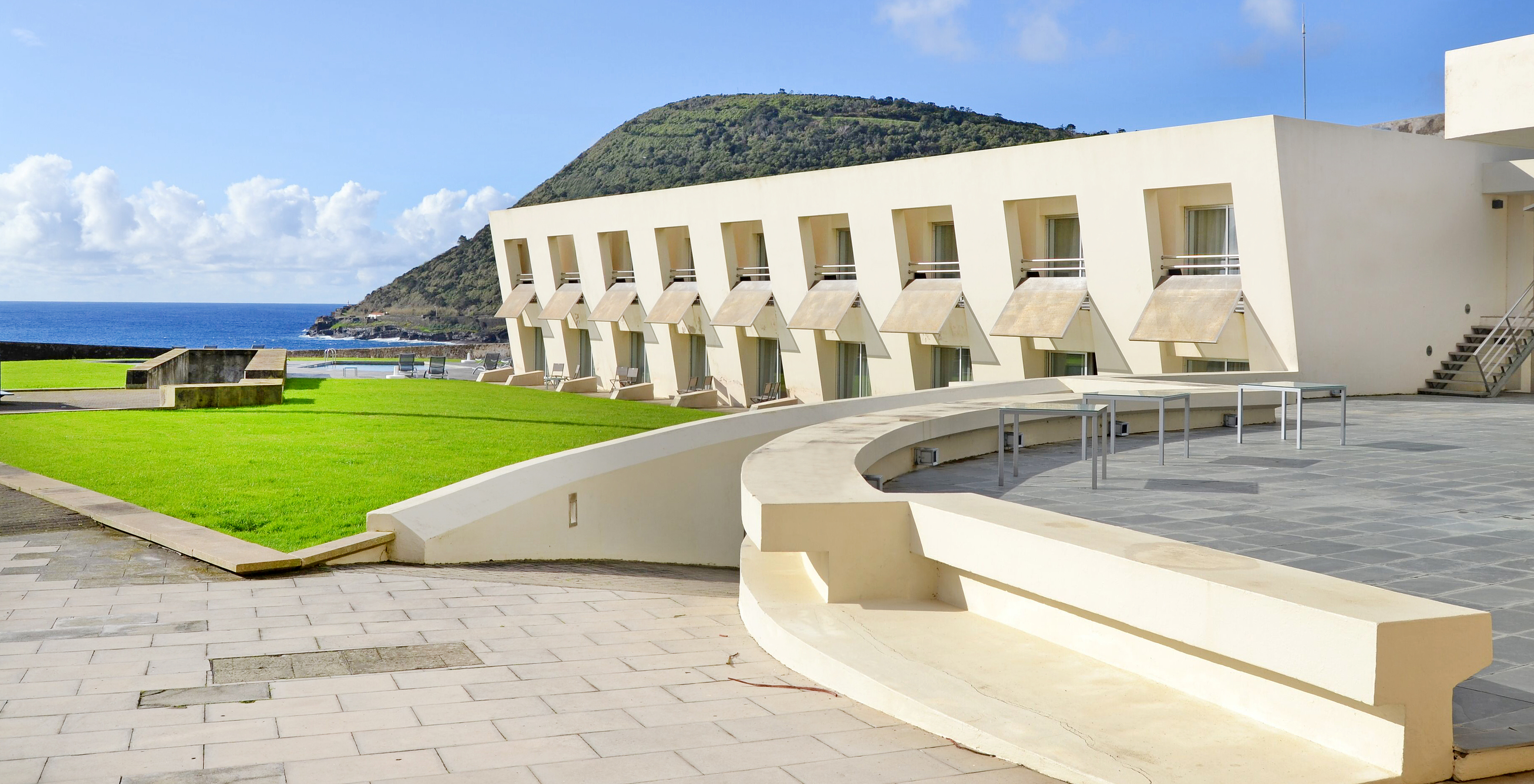 Fachada com as janelas dos quartos da Pousada Forte Angra do Heroísmo, com a piscina e o mar ao fundo