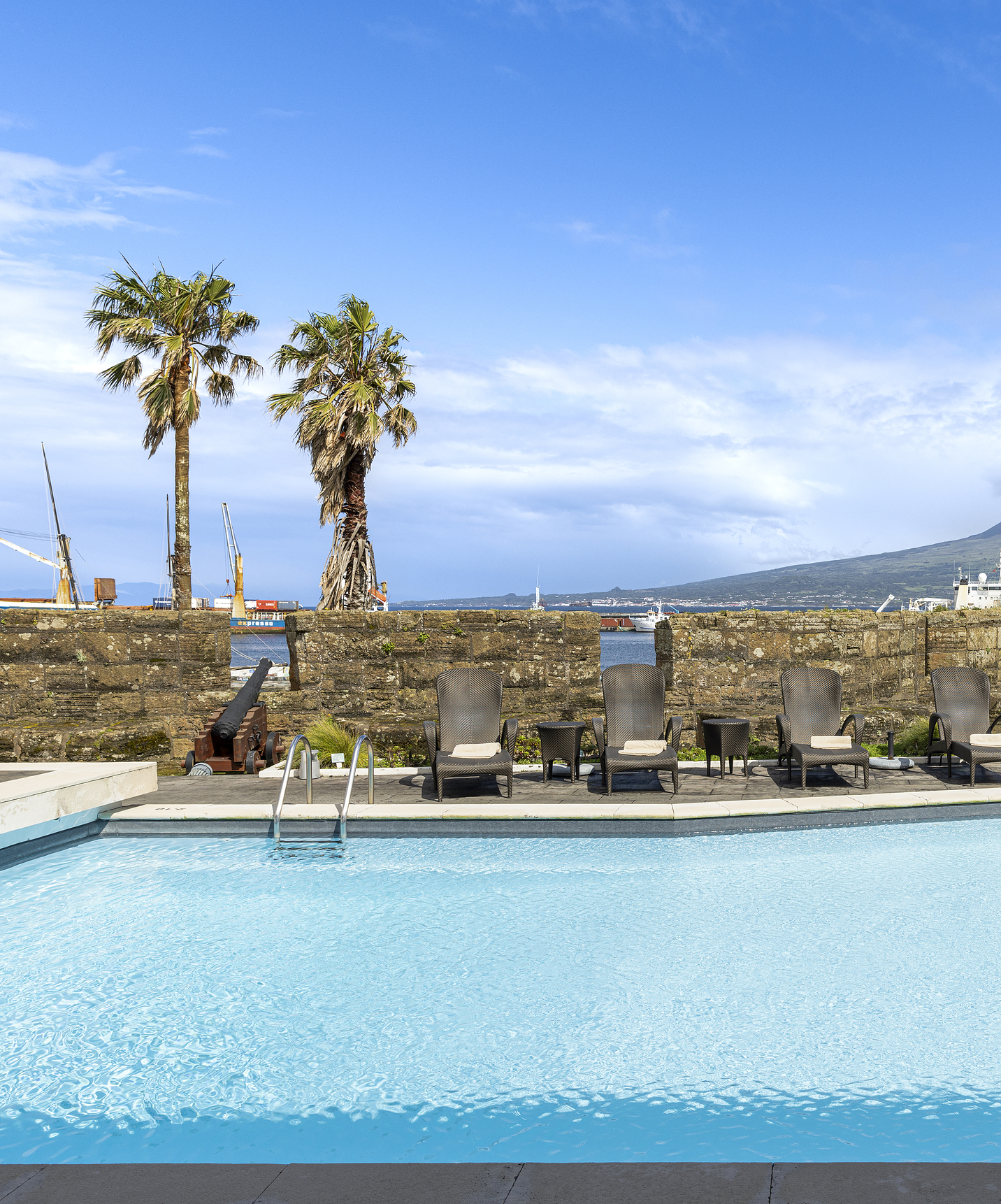 Piscina exterior da Pousada Forte horta, com espreguiçadeiras à volta, e vista para o mar