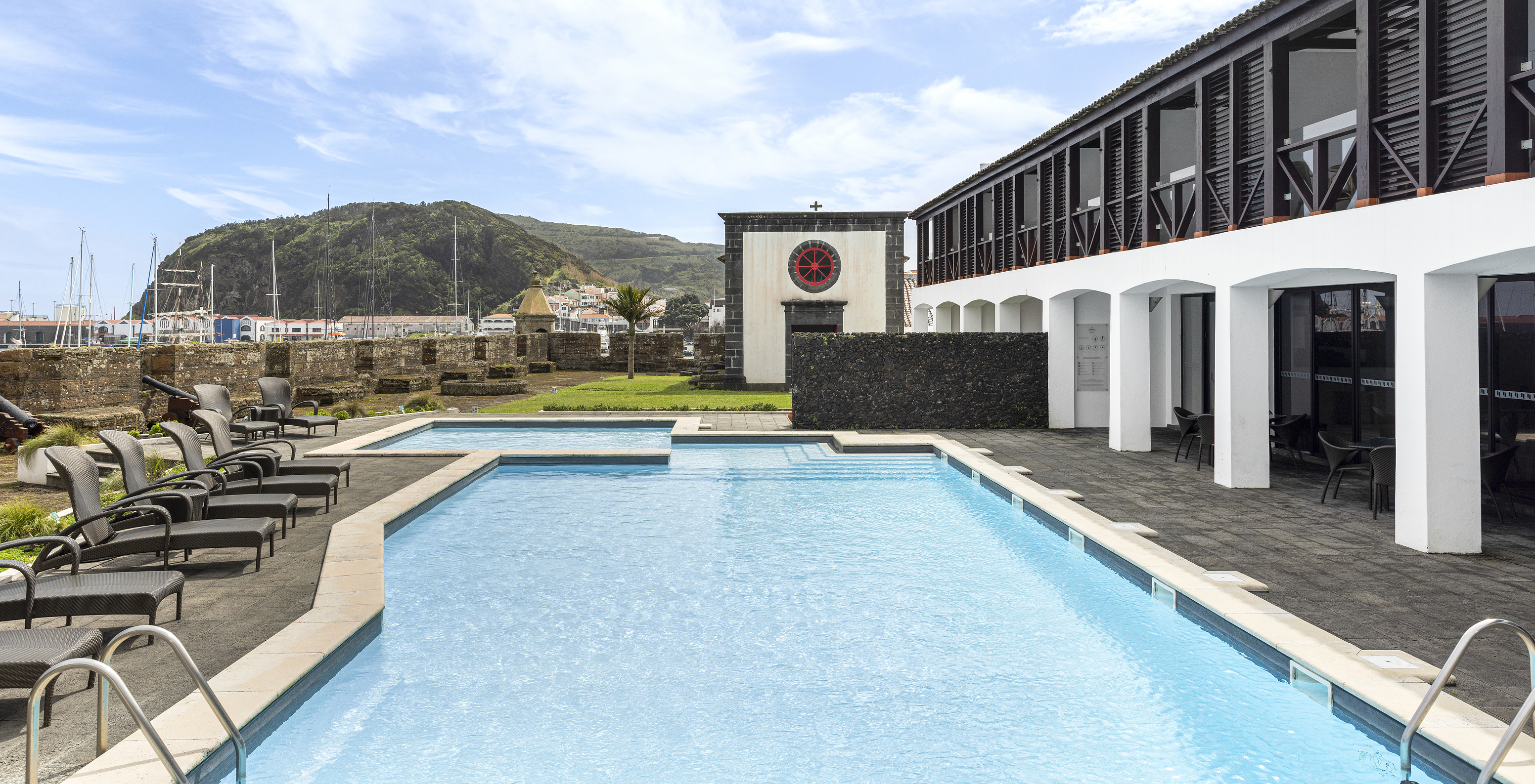 A Pousada Forte da Horta, hotel histórico nos Açores, tem uma piscina exterior com espreguiçadeiras e barcos