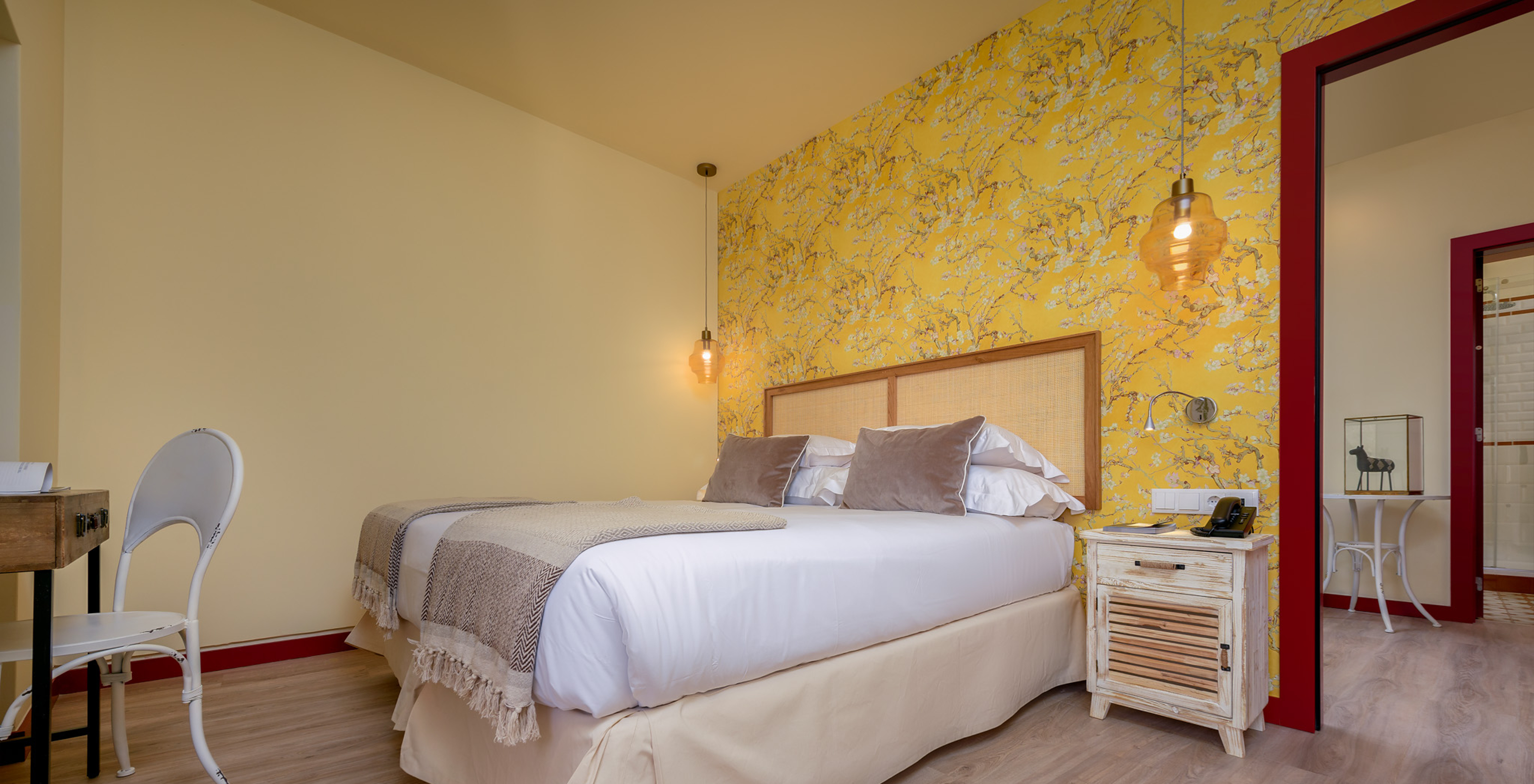 A Suite da Casa Lidador - Óbidos tem uma cama de casal, papel de parede florido em amarelo e uma mesa de cabeceira