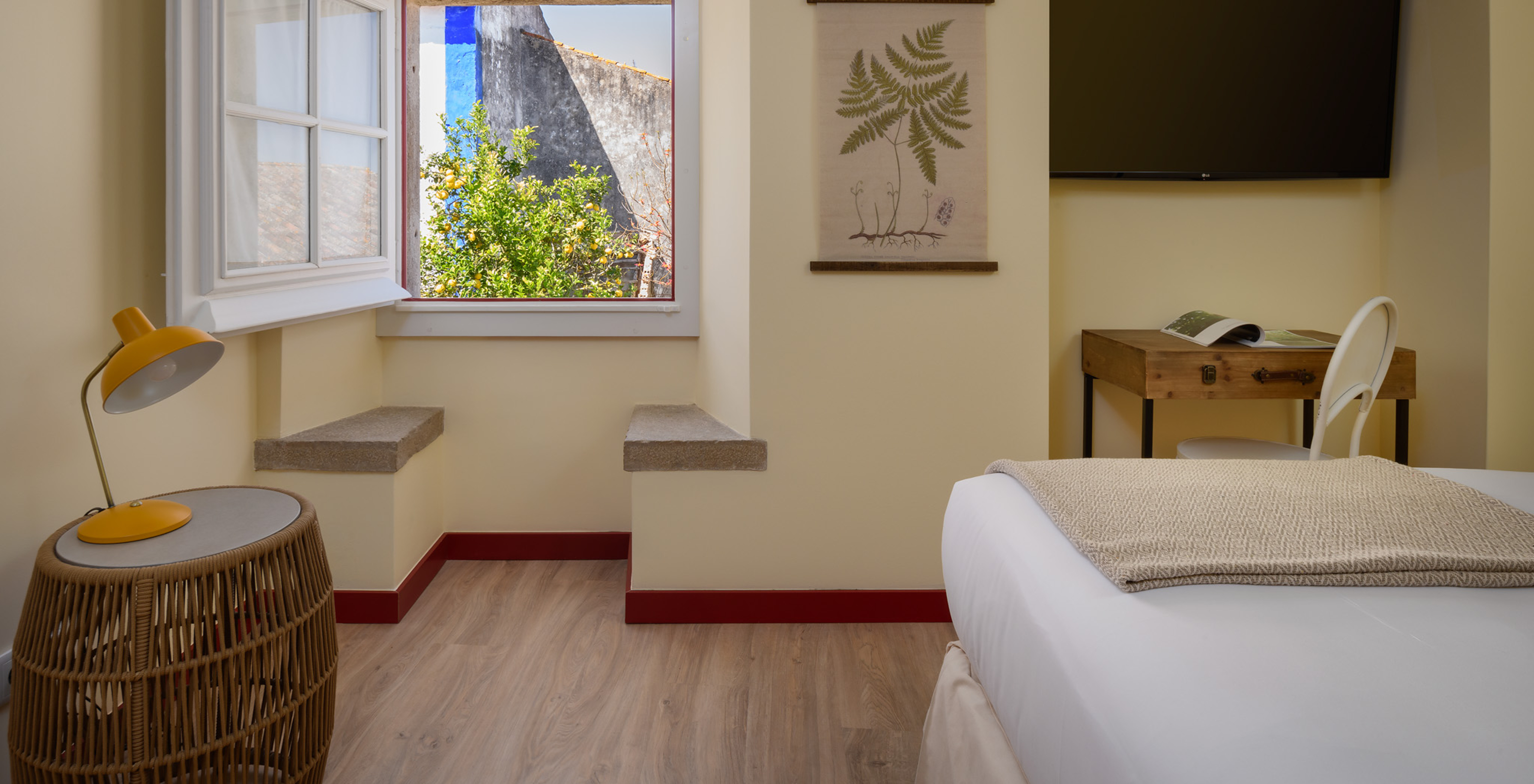 A Suite da Casa Lidador - Óbidos tem uma televisão, uma secretária e uma janela quadrada com dois bancos em pedra