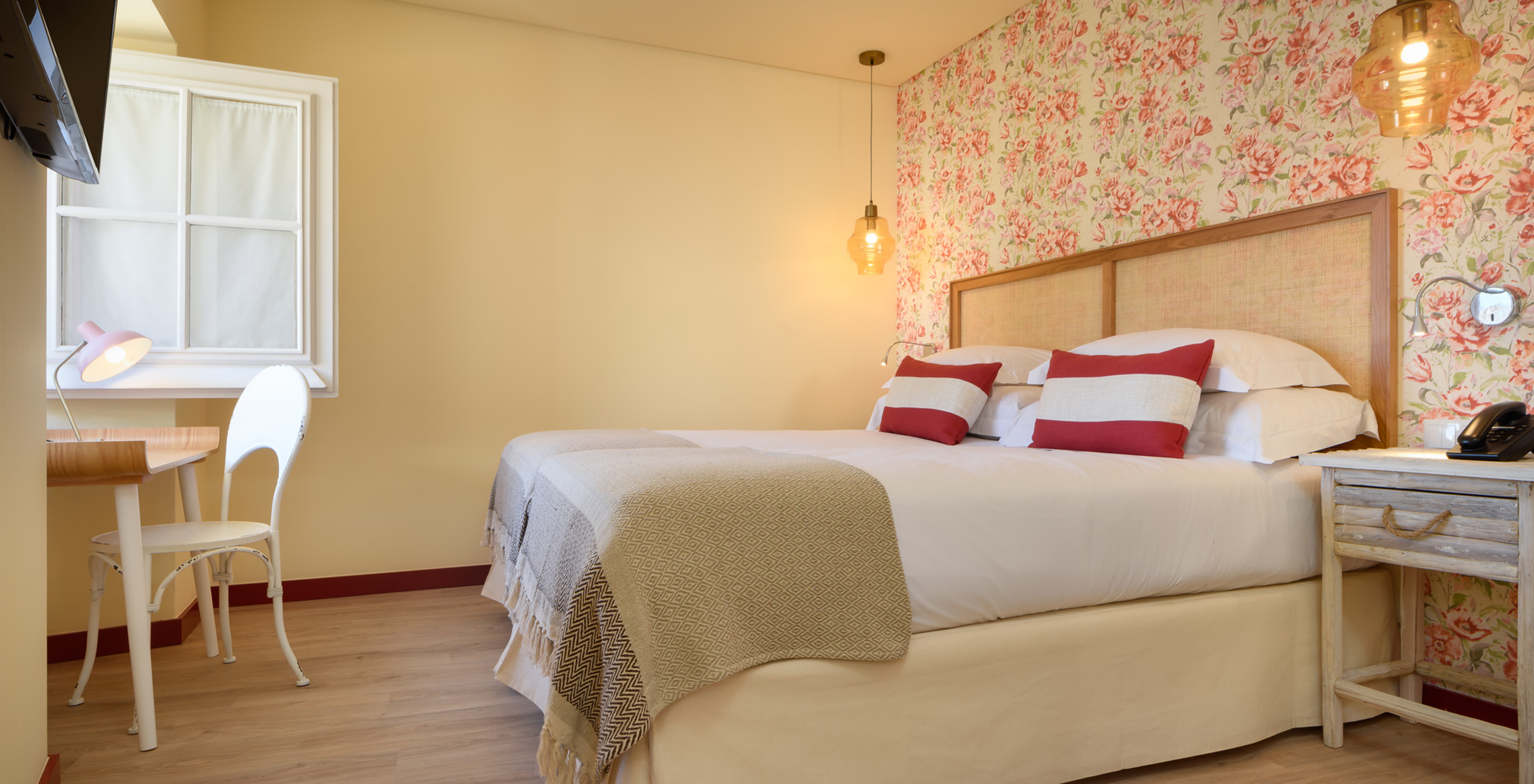 O Quarto Superior da Casa Lidador - Óbidos tem uma cama de casal, papel de parede florido e uma secretária em frente à janela