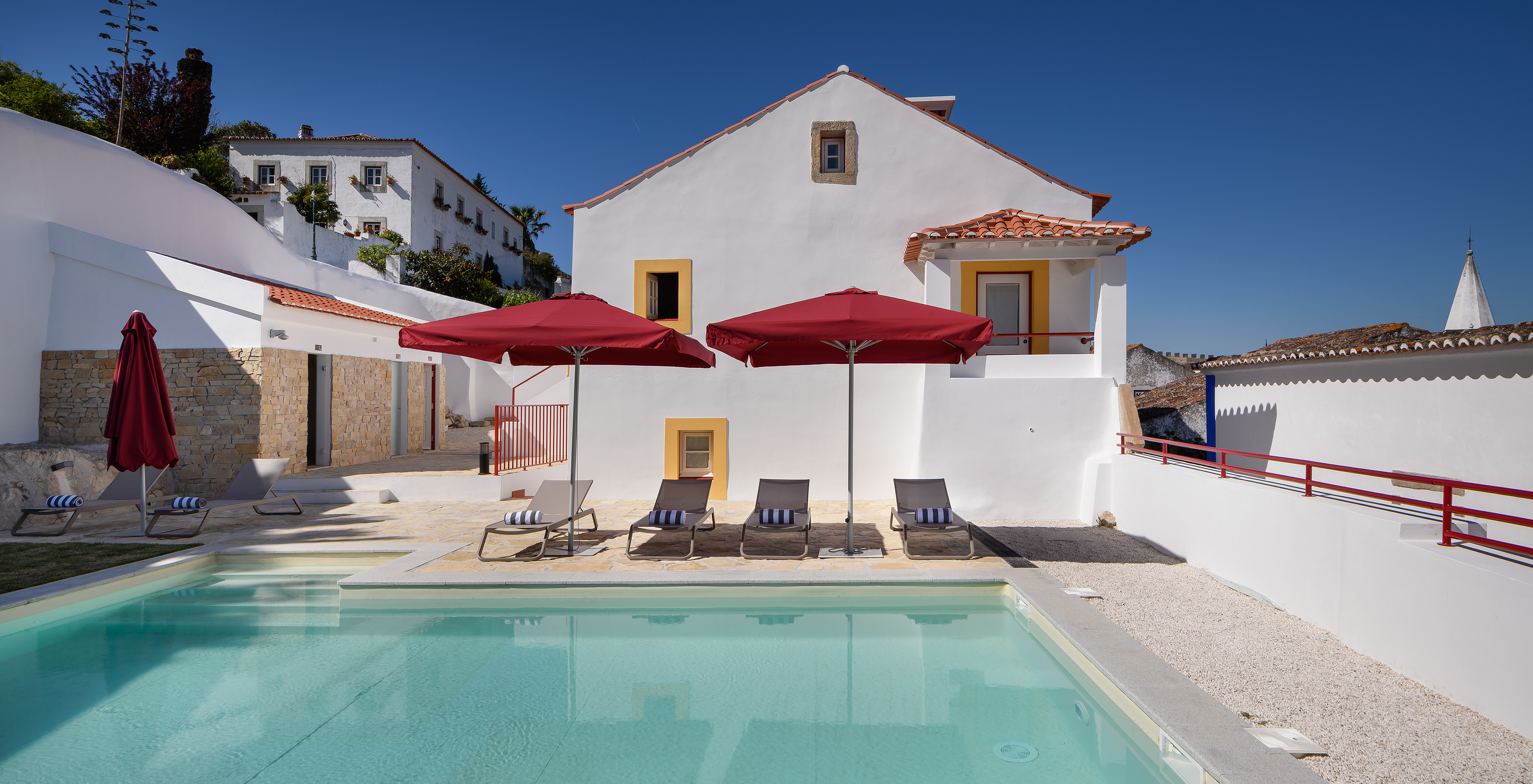 Piscina exterior, espreguiçadeiras e chapéus de sol na Casa Lidador - Óbidos, Hotel na Vila Medieval de Óbidos