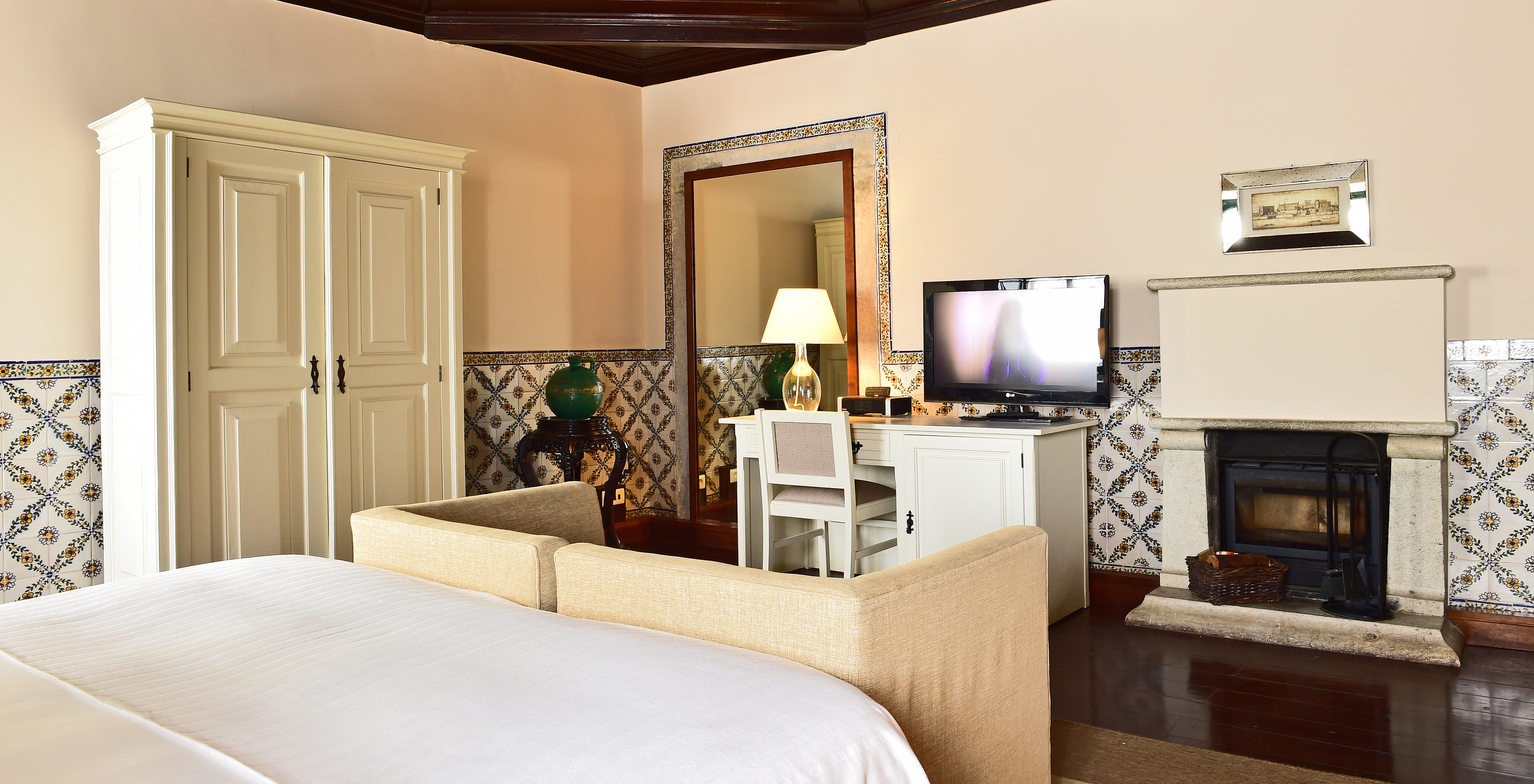 O quarto Large Family Casa do Castelo da Pousada Castelo Óbidos tem um sofá beje com televisão e lareira