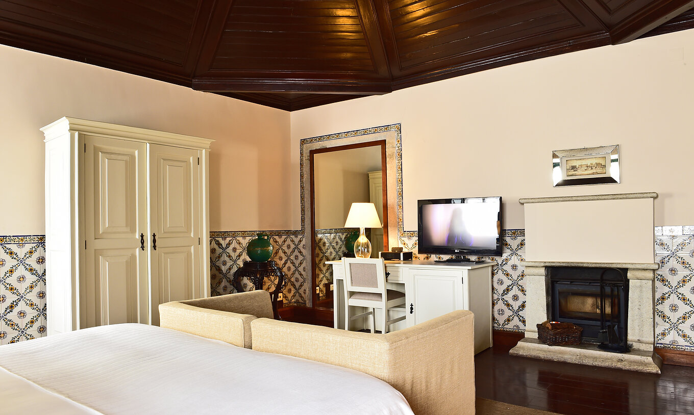 O quarto Large Family Casa do Castelo da Pousada Castelo Óbidos tem um sofá beje com televisão e lareira