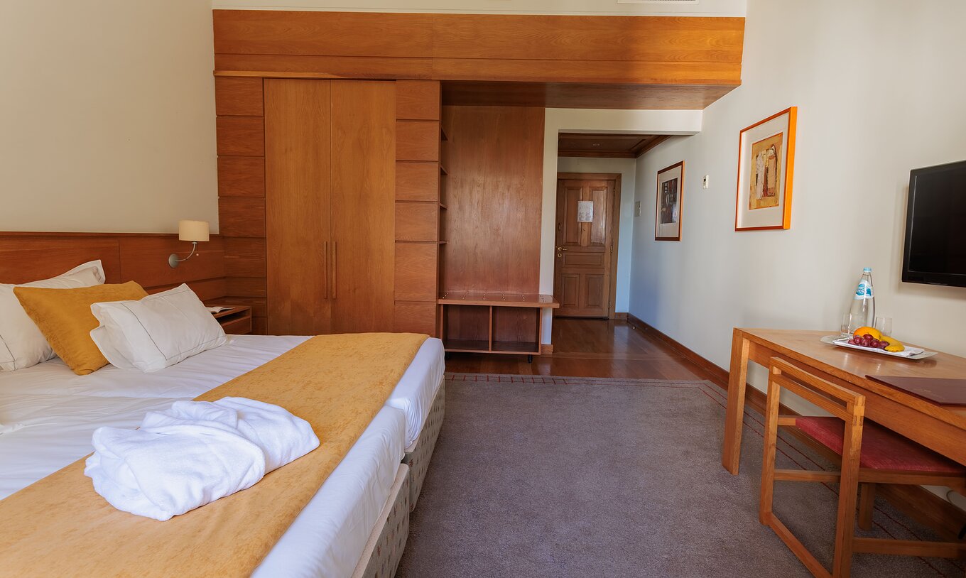 A Suite da Pousada Ourém tem uma cama de casal com um armário ao lado e televisão em frente à cama