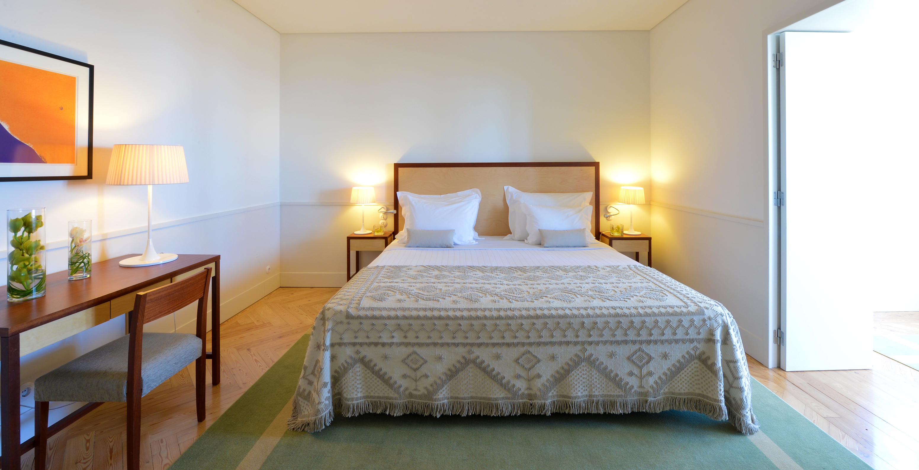 A Junior Suite da Pousada Serra da Estrela tem uma cama de casal, duas mesas de cabeceira e uma secretária com uma cadeira