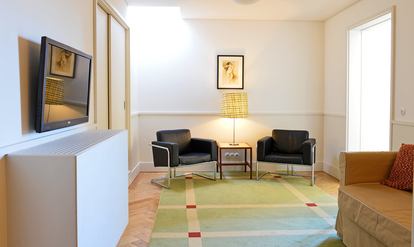 A Suite Presidencial da Pousada Serra da Estrela tem uma sala com um sofá, um quadro, duas poltronas e uma televisão