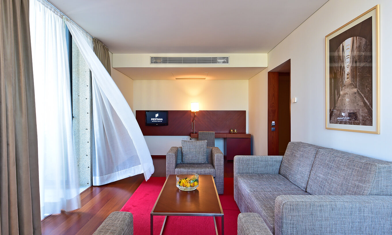 A Suite Mezzanine da Pousada Viseu conta com uma sala com dois cadeirões, um sofá, uma secretária e uma televisão