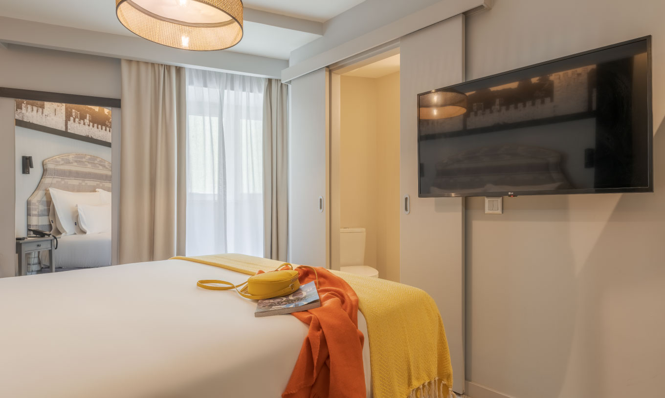 O Cozy da Pousada Alfama tem uma cama de casal, uma janela com cortinas brancas, um espelho e uma televisão