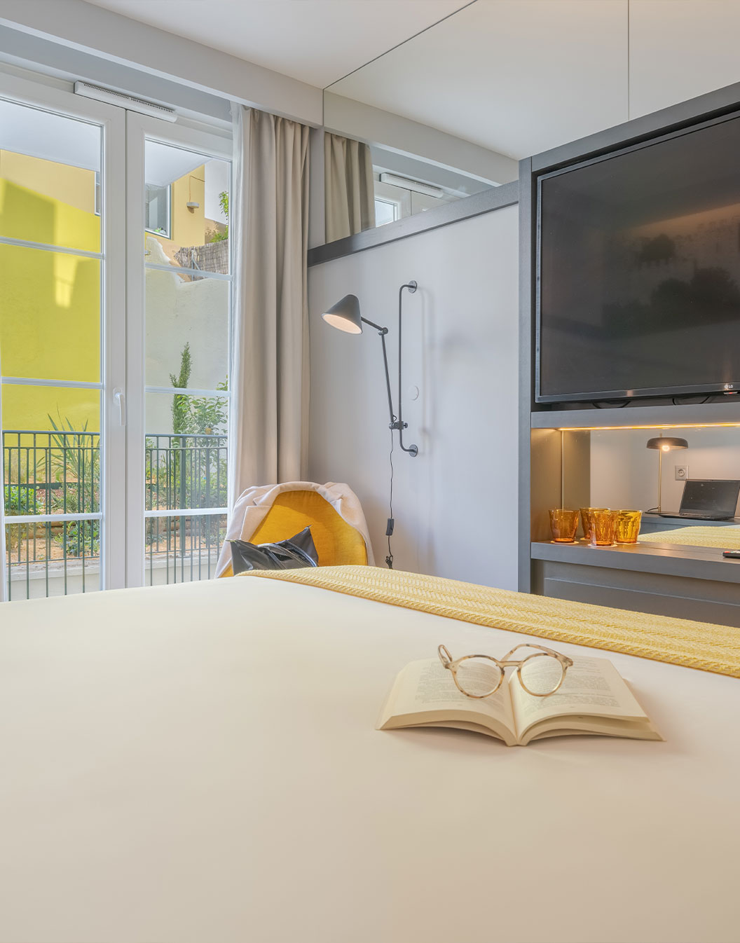 O Comfort Balcony da Pousada Alfama tem uma grande TV em frente à cama de casal e ao lado da janela do quarto