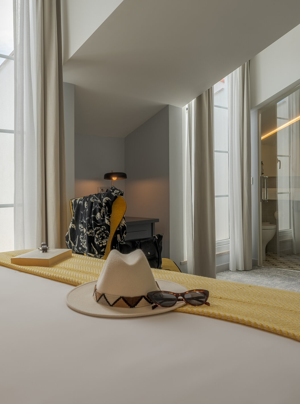 A Junior Suite da Pousada Alfama tem duas janelas grandes , uma televisão e uma casa de banho com porta transparente