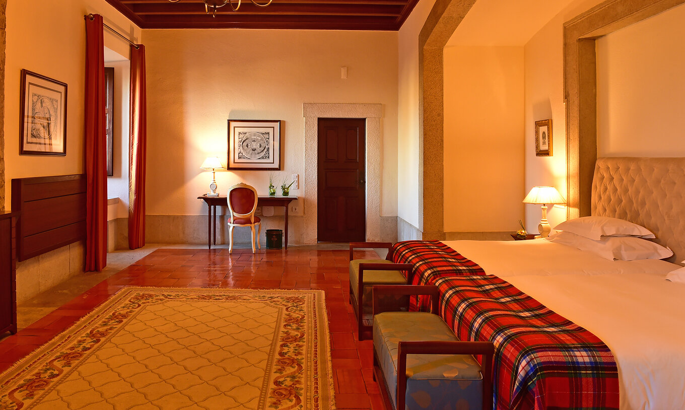 A Suite Standard da Pousada Castelo Palmela tem um quarto amplo com duas camas individuais, uma secretária e um tapete