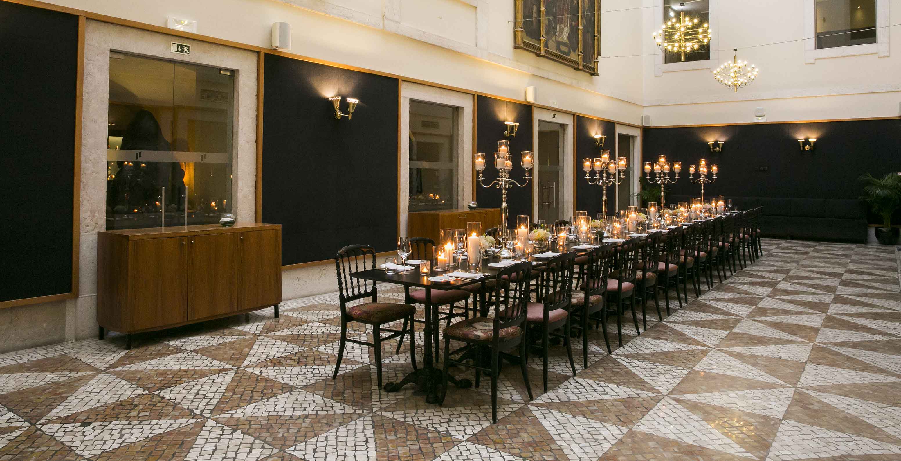 Terraço de eventos sofisticado no hotel histórico na Baixa de Lisboa, com candelabros e mesa decorada sobre piso de mosaico