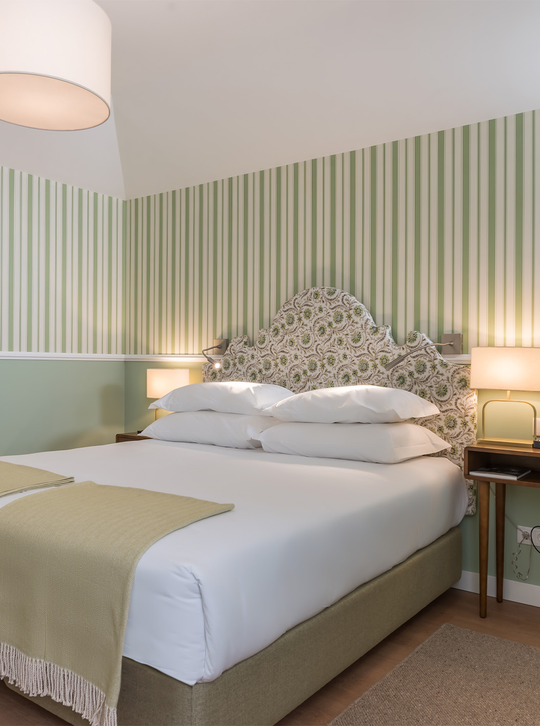 O Quarto Clássico do Pestana Churchill Bay tem uma cama de casal, papel de parede às riscas em tons verdes e uma mesa