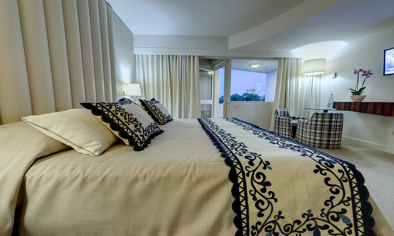 O Quarto Clássico da Pousada Bragança tem uma cama da casal, uma varanda com vista, e dois cadeirões com mesa de centro