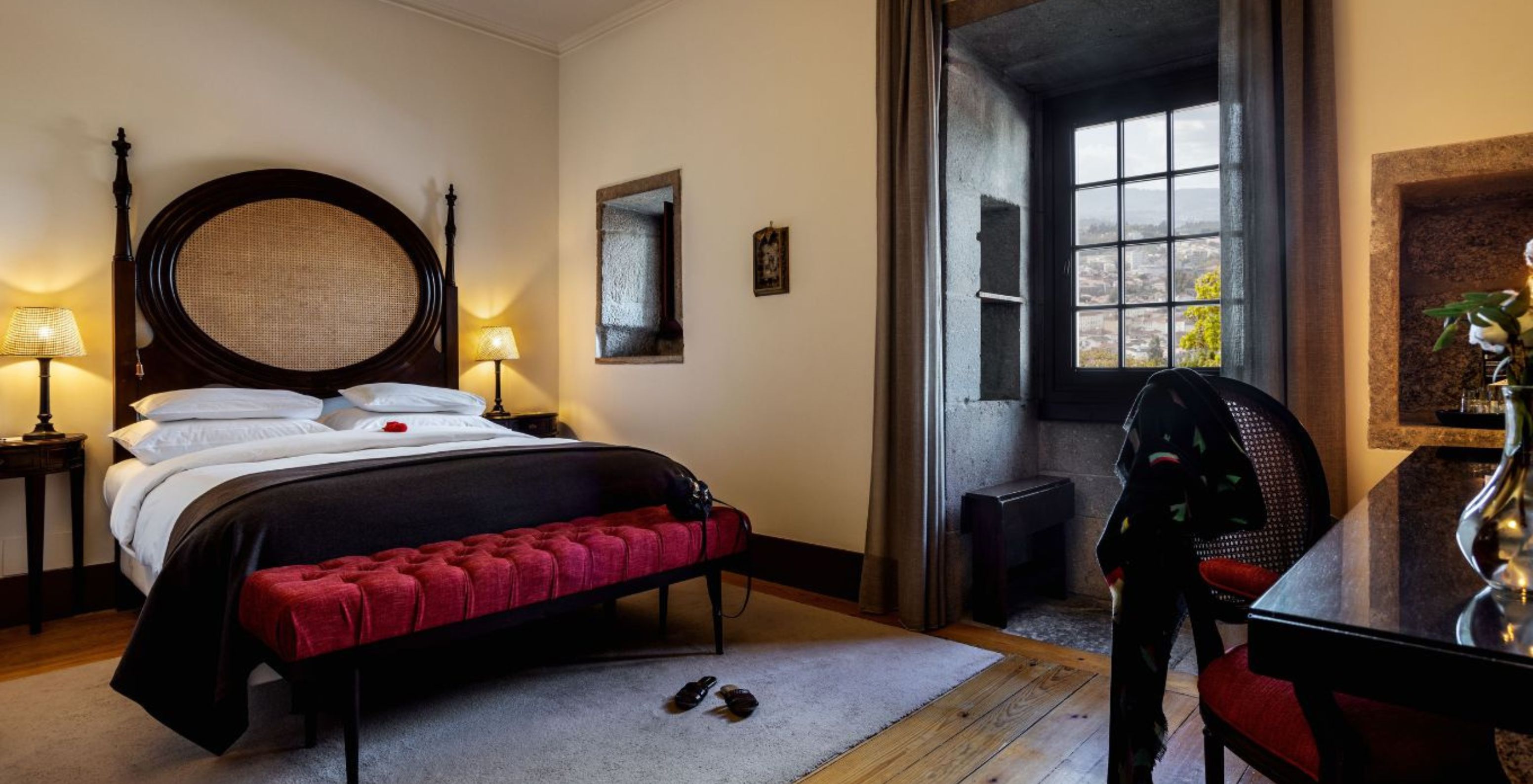 O Quarto Clássico da Pousada Mosteiro Guimarães tem uma cama de casal com cabeceira em madeira escura e palha