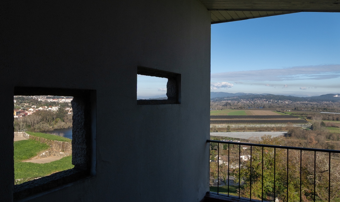 Vista do campo e das colinas através das janelas do quarto superior com terraço da Pousada Valença