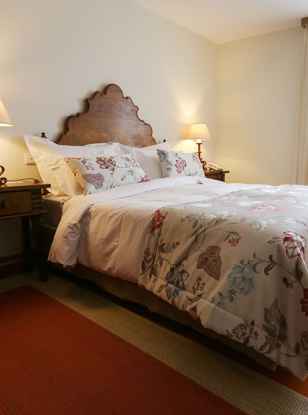 O Junior Suite da Pousada Valença tem uma cama de casal com uma colcha com flores e duas mesas de cabeceira