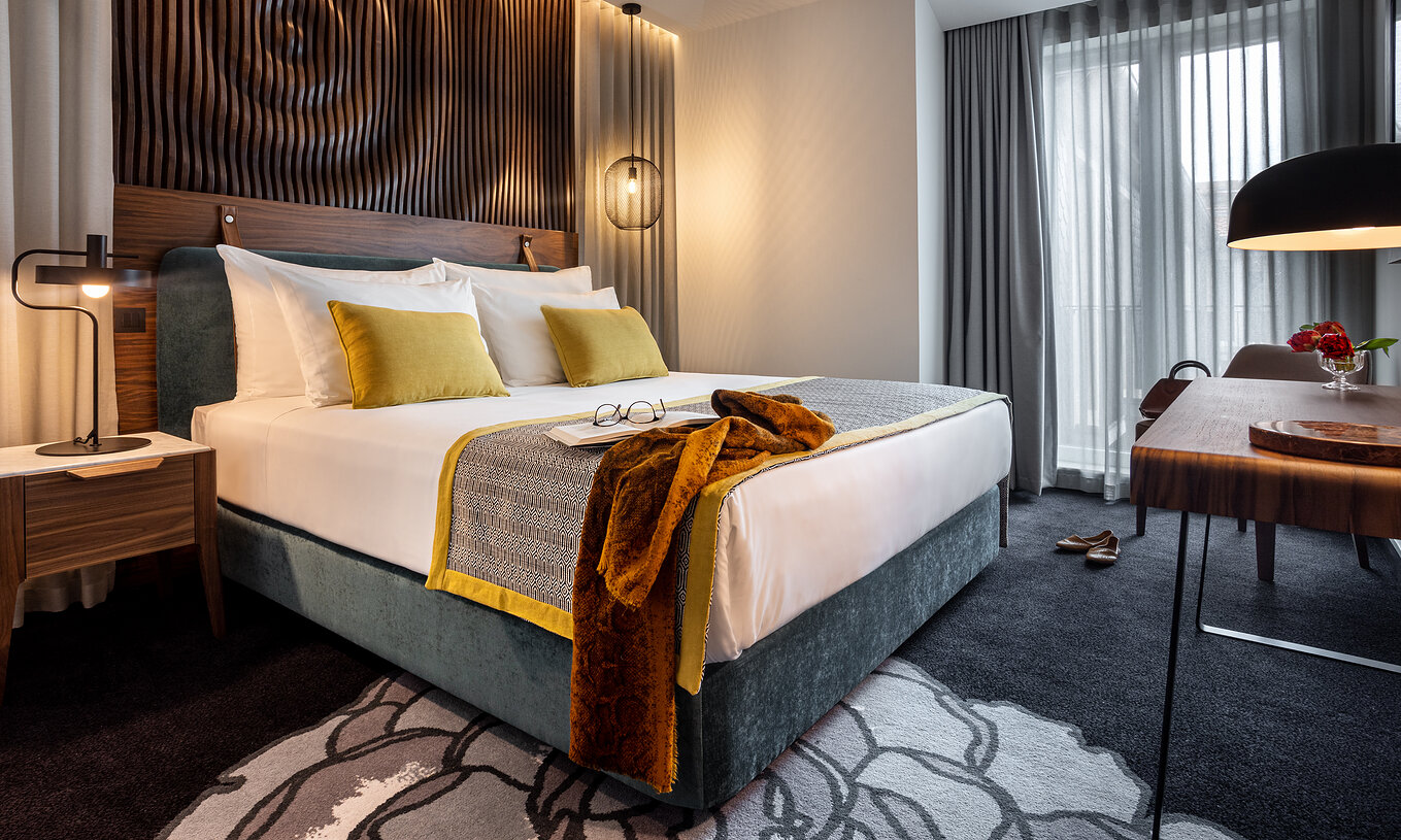 A Junior Suite da Pousada Porto - Rua das Flores tem uma cama de casal turquesa, lençóis brancos e cabeceira em madeira