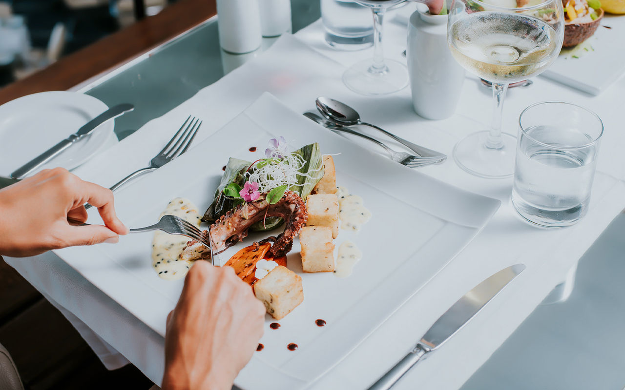 Weißer Teller mit Oktopus und gebratenem Mais, während einer Mahlzeit in einem Hotel der Pestana Hotels and Resorts