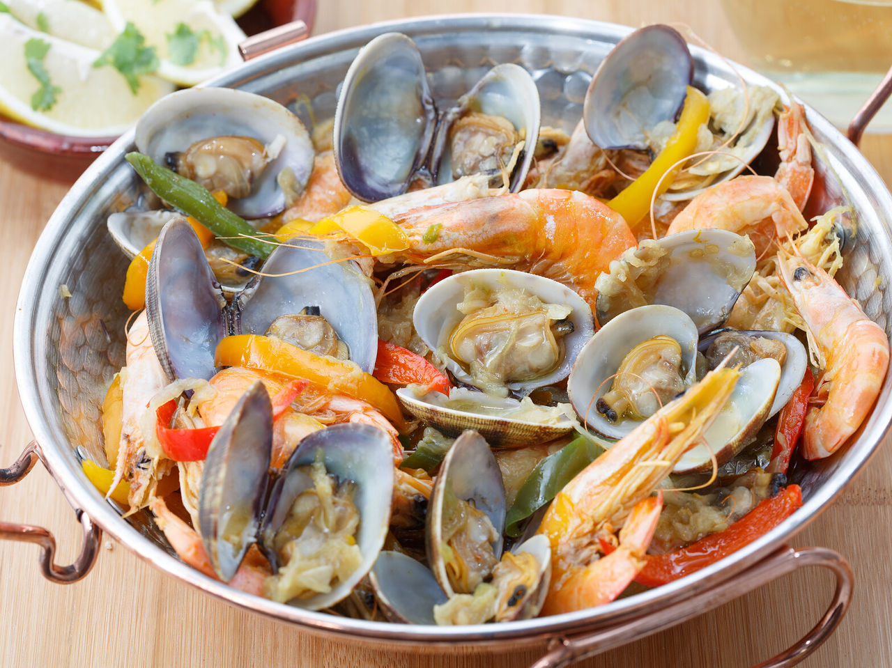 Typisches Gericht aus der Algarve-Region, eine Meeresfrüchte-Cataplana mit Muscheln, Garnelen und Paprika, mit Zitrone