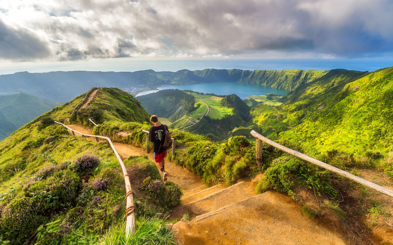 Mann geht auf einem Feldweg mit Blick auf die Lagoa das Sete Cidades, Insel São Miguel, Azoren