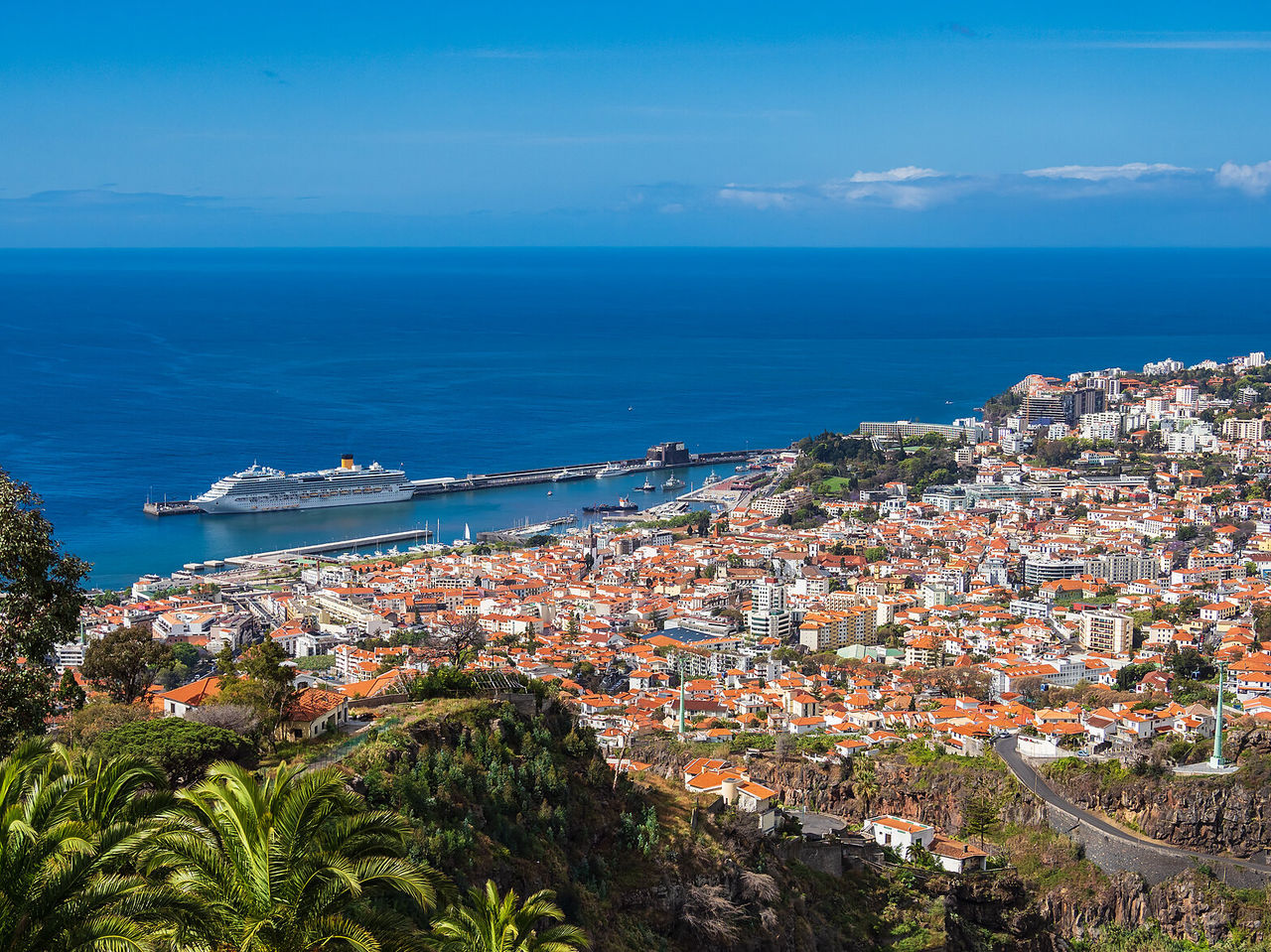 Blick auf die Stadt Funchal, voller Farben und am Meer, mit einem Kreuzfahrtschiff im Hintergrund