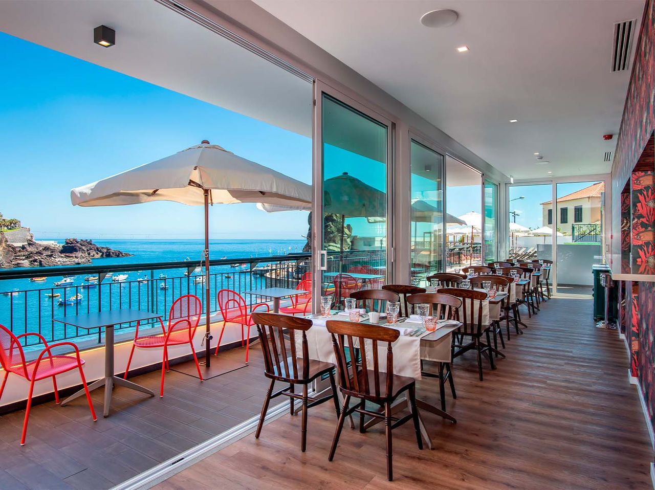 Das Restaurant Pier One Grill Terrace im historischen Hotel in Câmara de Lobos, Madeira, hat Tische innen und außen
