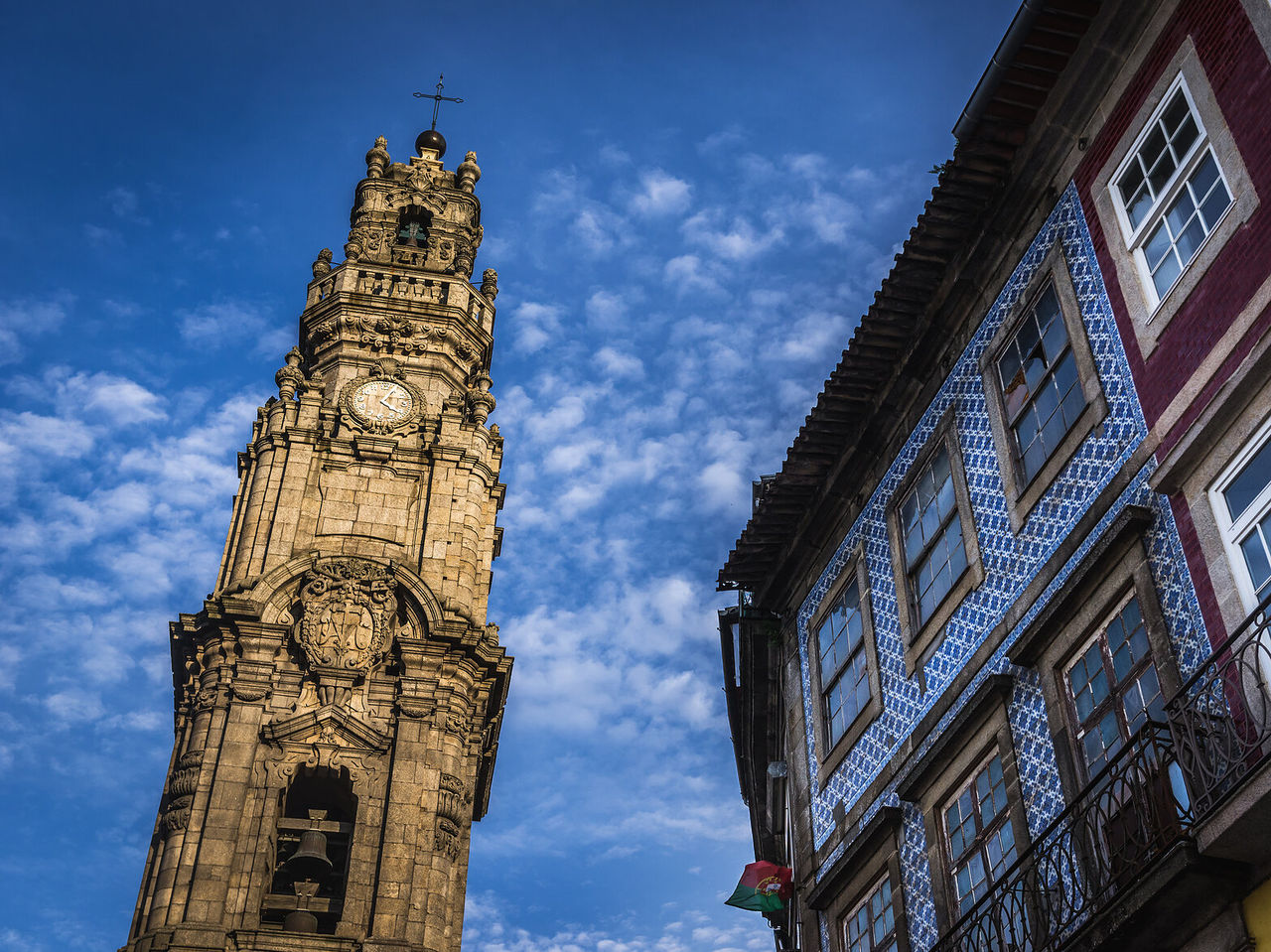Imposanter Clérigos-Turm, der sich gegen den blauen Himmel abhebt, während ein Nachbargebäude die typische Architektur zeigt