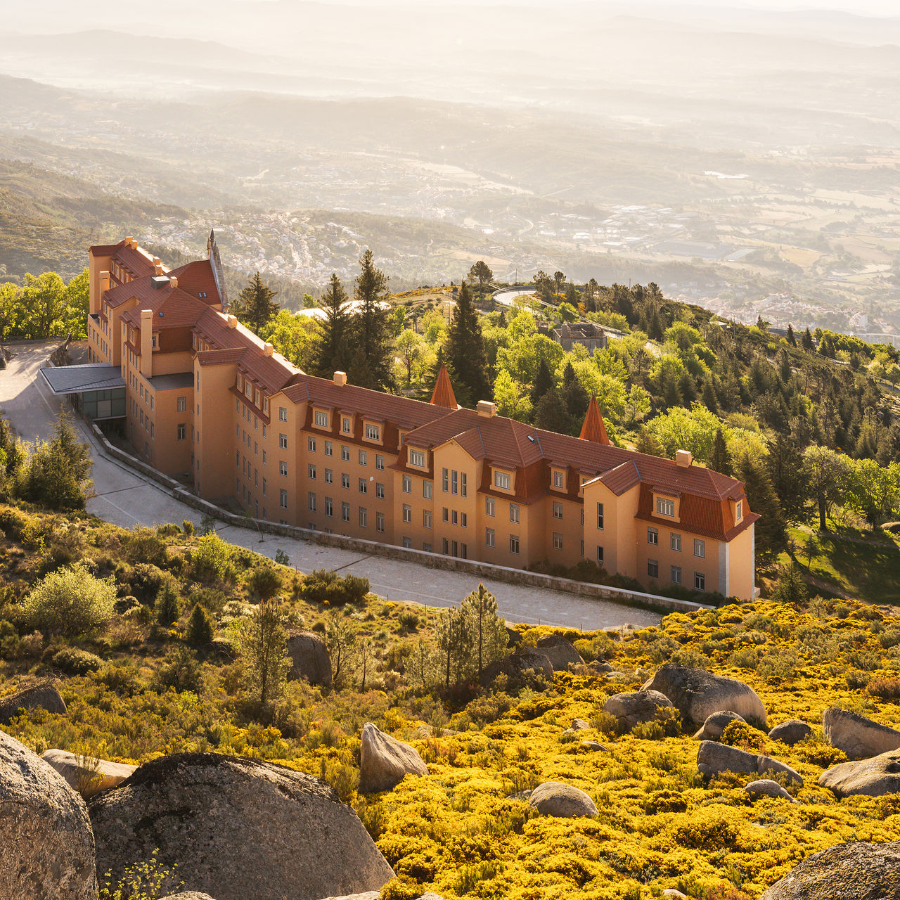 Gebäude der Pousada Serra da Estrela, mitten in der Serra da Estrela, mit üppiger Vegetation und Bergen im Hintergrund
