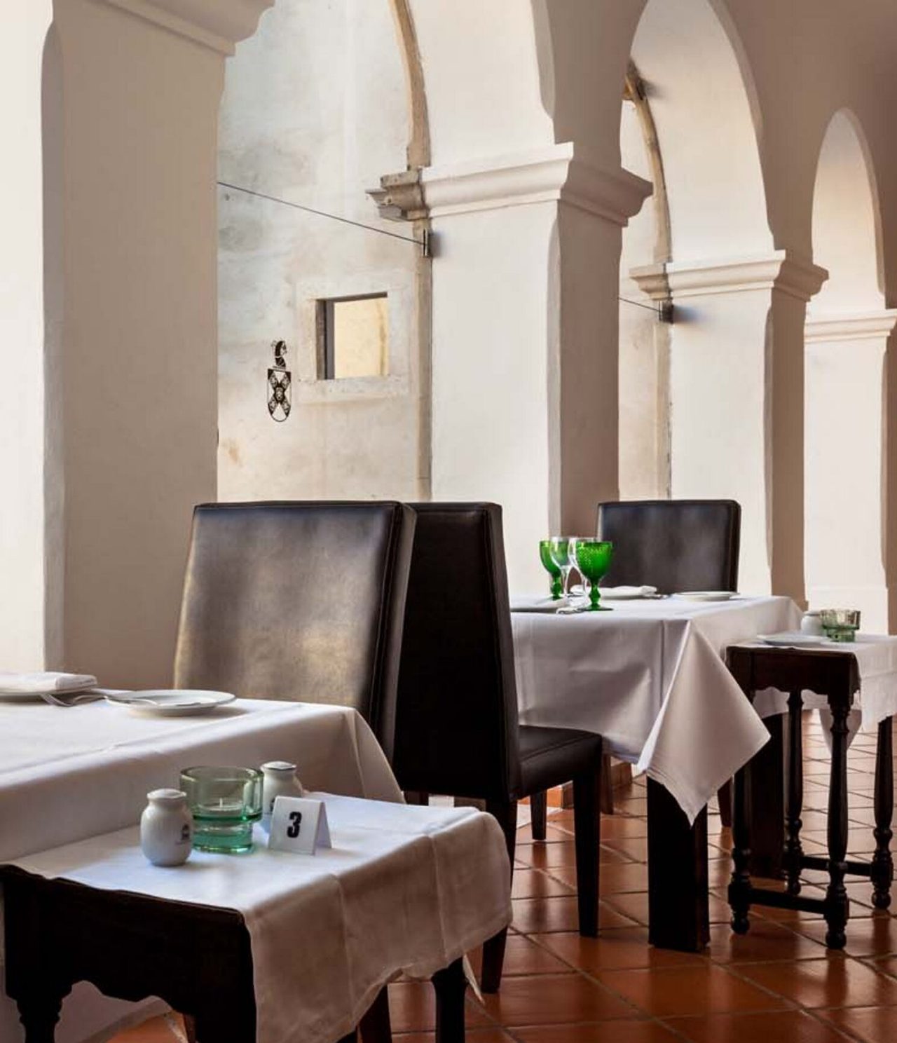The Pousada Castelo Alvito restaurant, of the Historic Hotel in Alvito, has several tables set and windows with arches