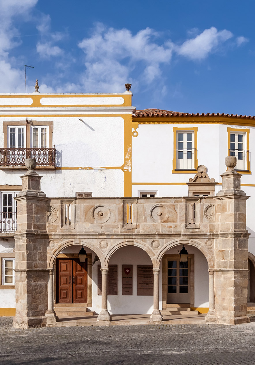 Varanda de pedra histórica da Pousada Mosteiro Crato, com arcos e detalhes arquitetónicos sob céu azul