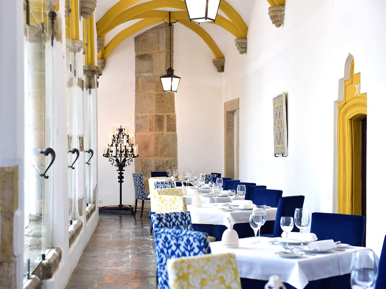 The restaurant Loios, at the Historic Hotel in Évora, has white tables, blue chairs, and natural light
