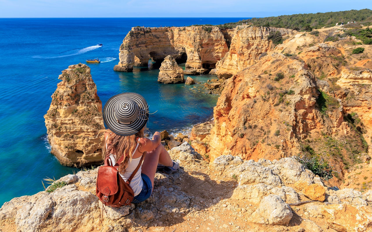 Explore Hotels in the Algarve overlooking visitors admiring coastal cliffs and blue ocean caves beside clear turquoise water