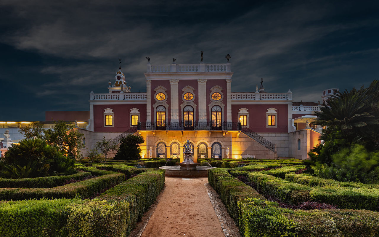 Exterior view of Pousada Palácio Estoi, a historic hotel in Faro, surrounded by well-kept gardens and an outdoor pool