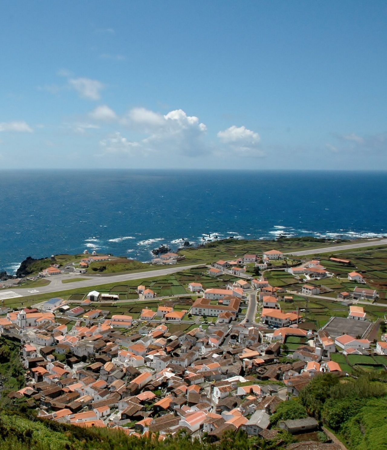 Aerial view of Corvo Island, with its airstrip, picturesque village, and natural pool, surrounded by deep blue sea