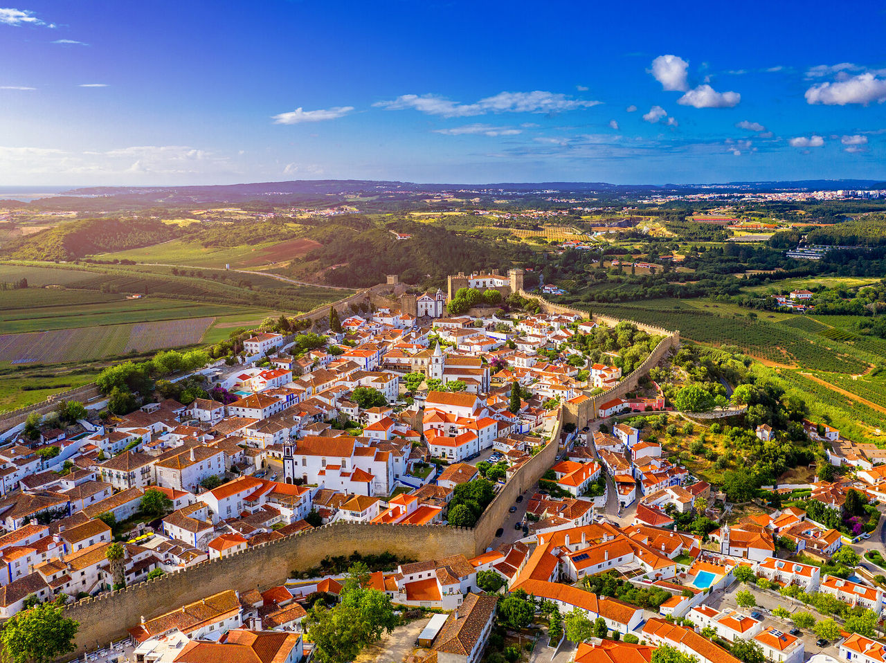 Explore Hotels in Central Portugal with an aerial view of a walled hilltop town amid green countryside